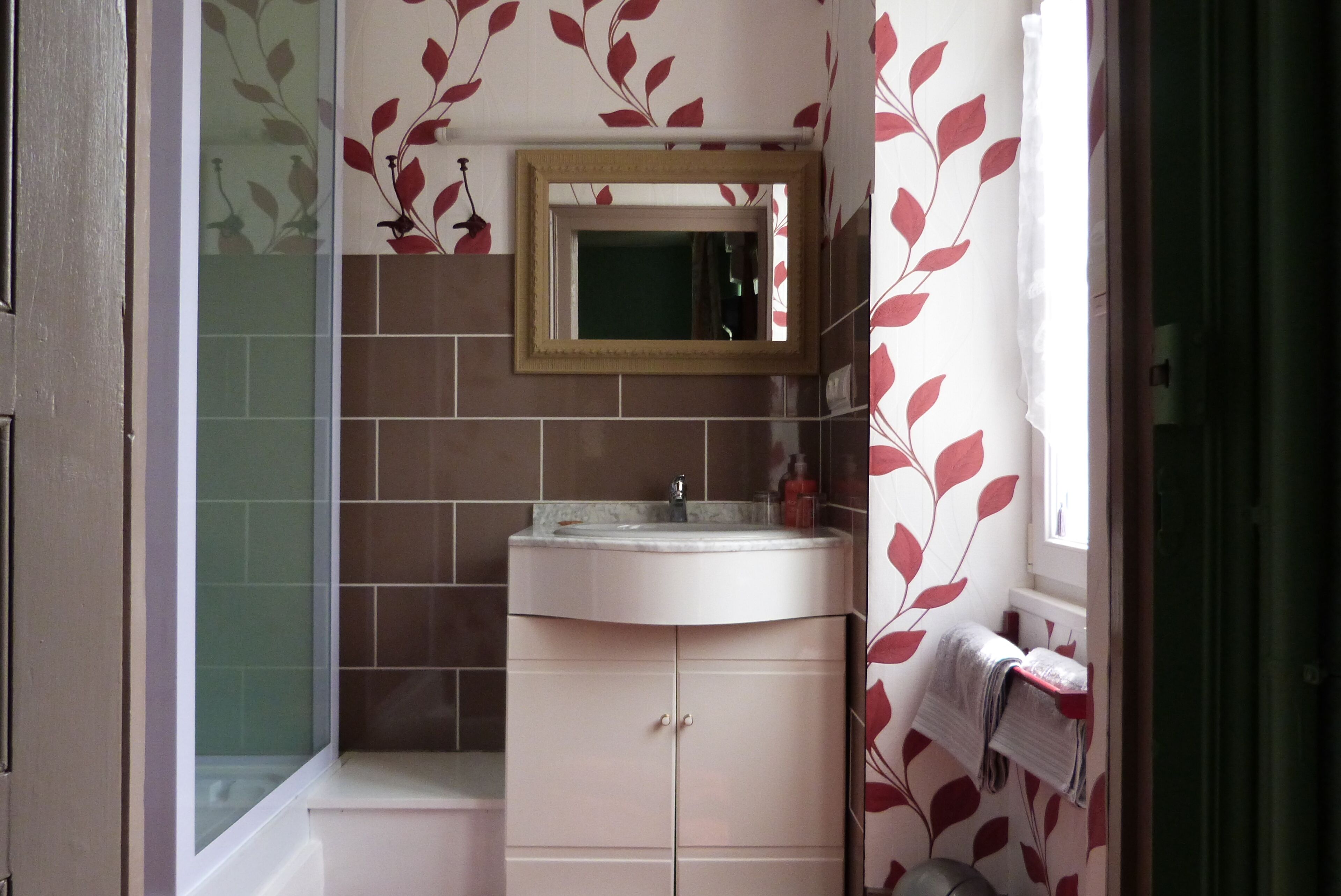 Een badkamer met een wastafel, spiegel en betegelde wanden.