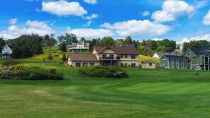 A golf course with a clubhouse and residential buildings in the background. - 6BR Luxury Escape w/ Indoor Pool Boat Dock Avail (Swanton)