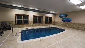 An indoor swimming pool with a stone wall, a wooden chair, and a sign for 'Bearly Fine Resort'.