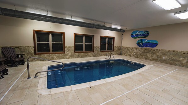 An indoor swimming pool with a stone wall, a wooden chair, and a sign for 'Bearly Fine Resort'.