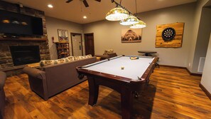 A pool table in a room with a fireplace, a sofa, and a dartboard. - 6BR Luxury Escape w/ Indoor Pool Boat Dock Avail (Swanton)