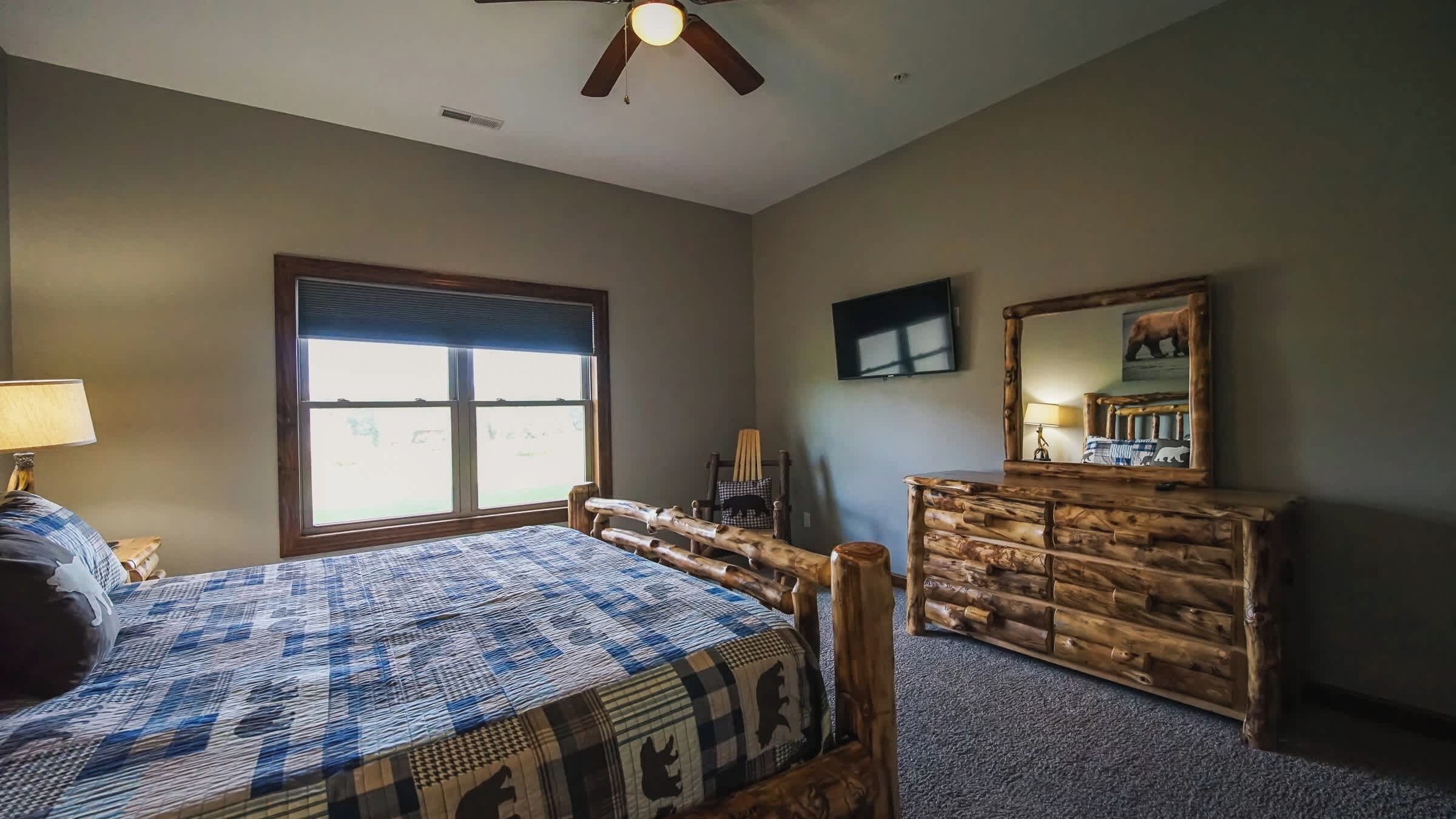 A bedroom with a bed, a dresser, a television, and a window.