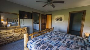 A bedroom with a wooden bed frame, a dresser, a ceiling fan, and a bathroom visible through an open door. - 6BR Luxury Escape w/ Indoor Pool Boat Dock Avail (Swanton)