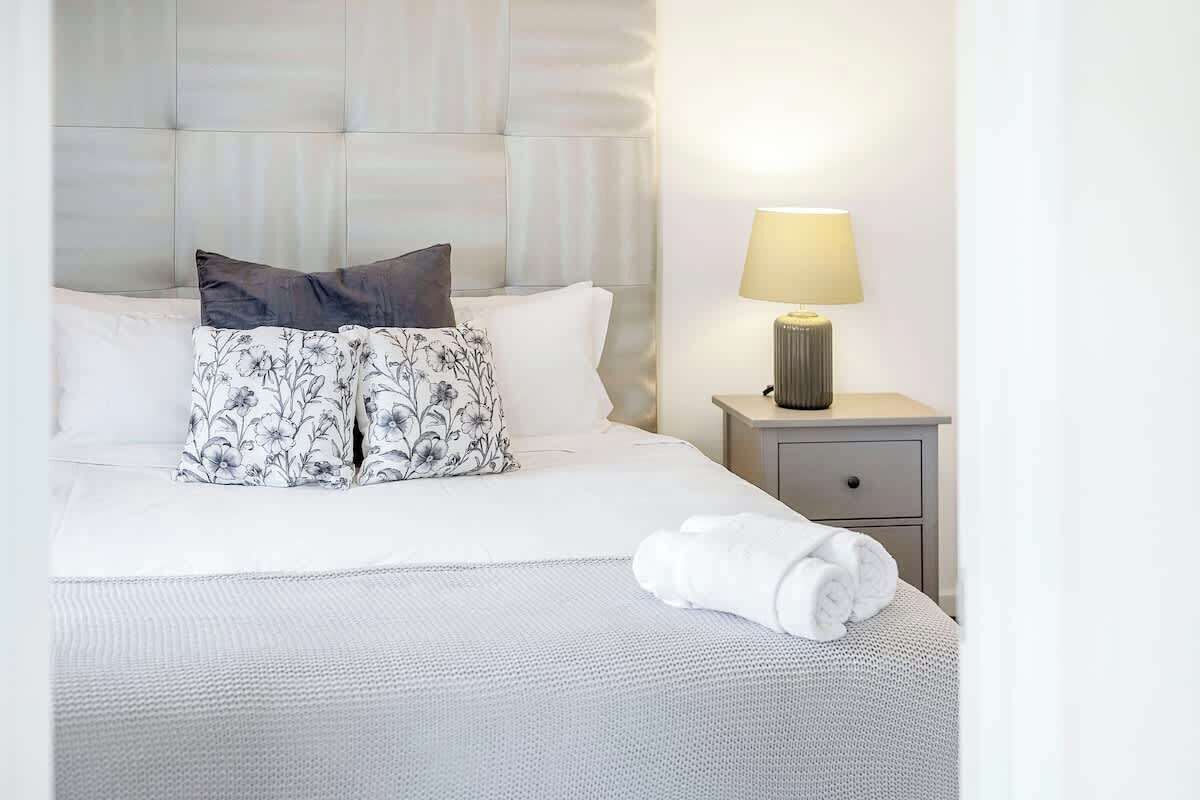 Your restful retreat awaits! Sink into the plush comfort of this bed, surrounded by soft pillows and the gentle glow of the bedside lamp. 