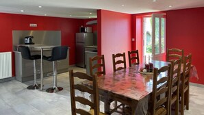 A compact kitchen with modern appliances, a dining area with a wooden table and chairs, and a bright red accent wall.