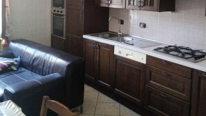 Una cocina compacta con armarios de madera oscura, una encimera blanca y una estufa a gas.