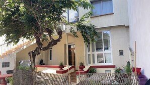 Un edificio con una zona de estar al aire libre techada, una escalera y plantas en macetas.
