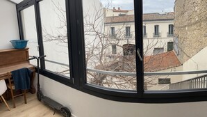 Una habitación con un ventanal grande, un escritorio de madera, un tazón azul y una scooter.
