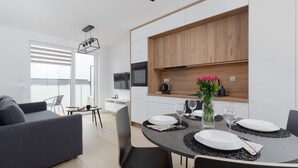 Una cocina moderna con armarios de madera, una mesa de comedor dispuesta con platos y vasos, y un sofá en la zona de estar contigua.