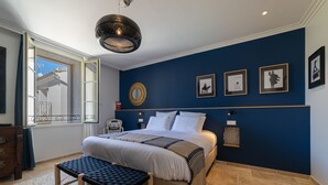 Une chambre à coucher avec un lit, un banc et une œuvre d’art accrochée au mur.