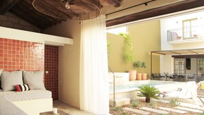 Un espace de vie extérieur moderne, doté d’une piscine, de coins salon et de plantes en pot.
