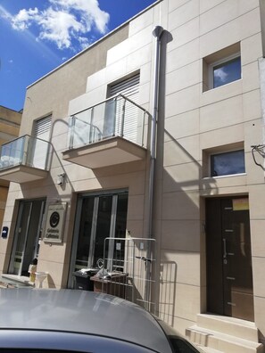A building with a cafe sign, a gated entrance, and a car parked in front. - Like at home 28 (Sava)