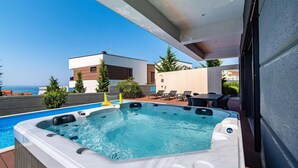 Ein Pool auf dem Dach mit Whirlpool, Liegestühlen und Meerblick.