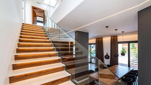 Eine moderne Treppe mit Holzboden und Glasgeländern, die zu einem Essbereich mit Holztisch und Stühlen führt.