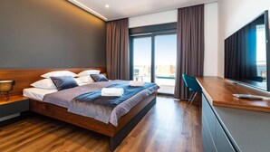 Ein modernes Hotelzimmer mit einem großen Bett, einem Schreibtisch, einem Flachbildfernseher und Blick auf die Stadt.