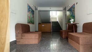 A hallway with two brown cushioned seating areas, a staircase, and two wall-mounted paintings.