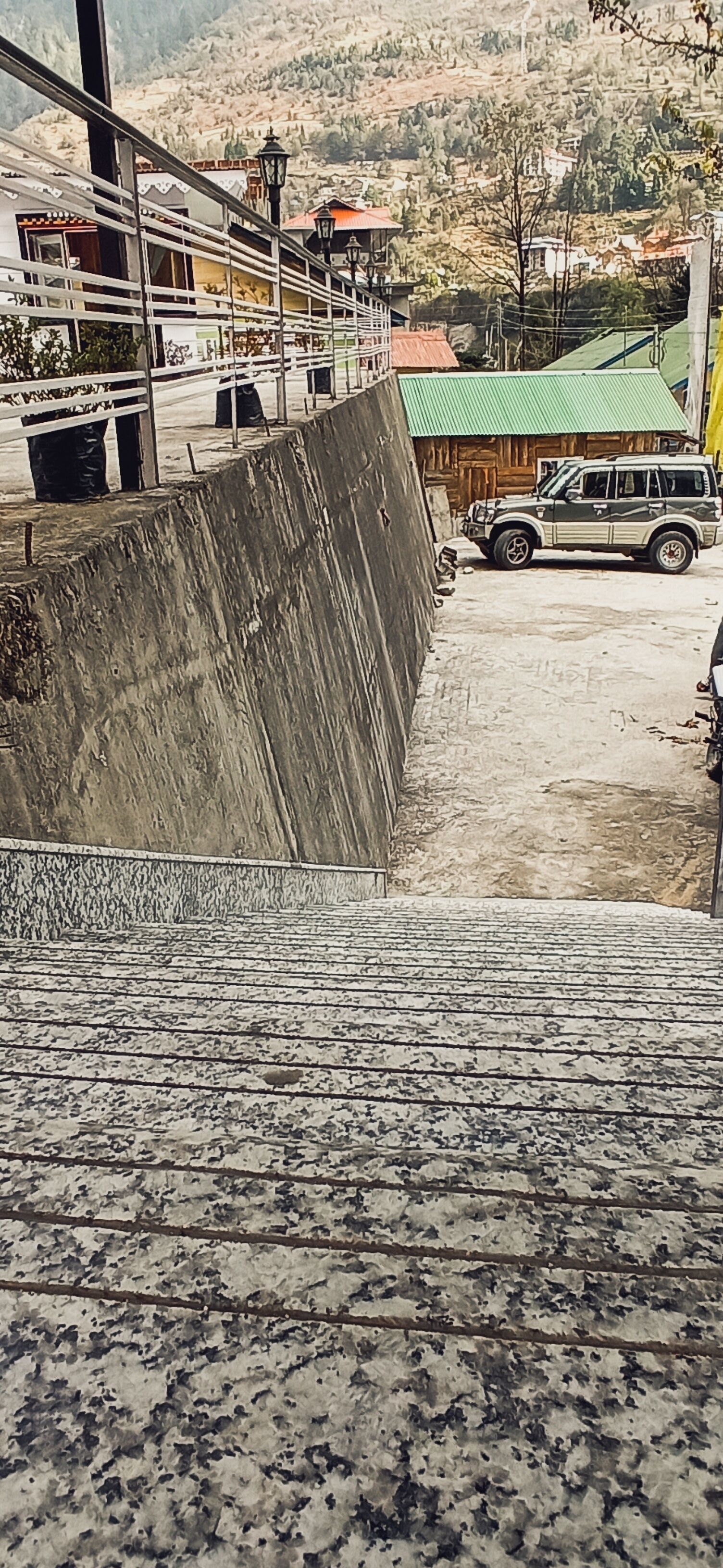 A staircase leading down to a parking area with a vehicle parked nearby.