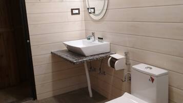 A bathroom with a toilet, sink, and a mirror.