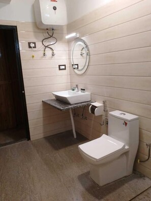 A bathroom with a white toilet, a sink with a mirror above it, and a wall-mounted water heater.