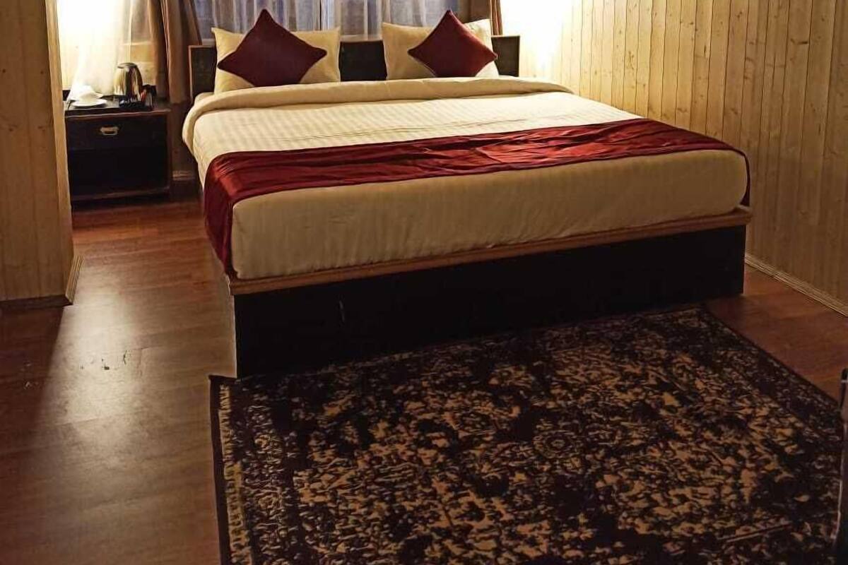 A bedroom with a bed, curtains, a nightstand, and a rug.