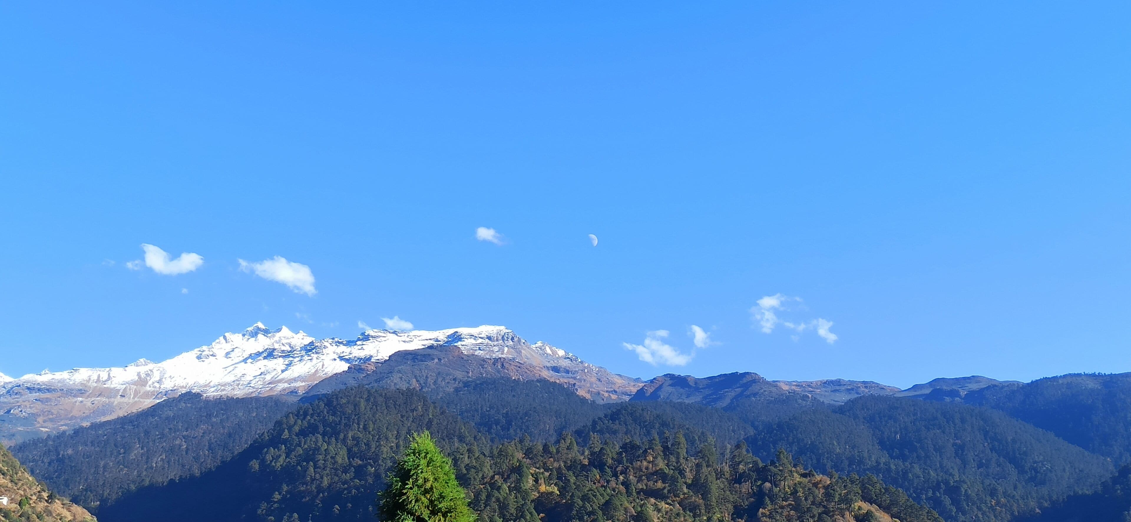 Paisaje montañoso con picos nevados y un cielo azul despejado.