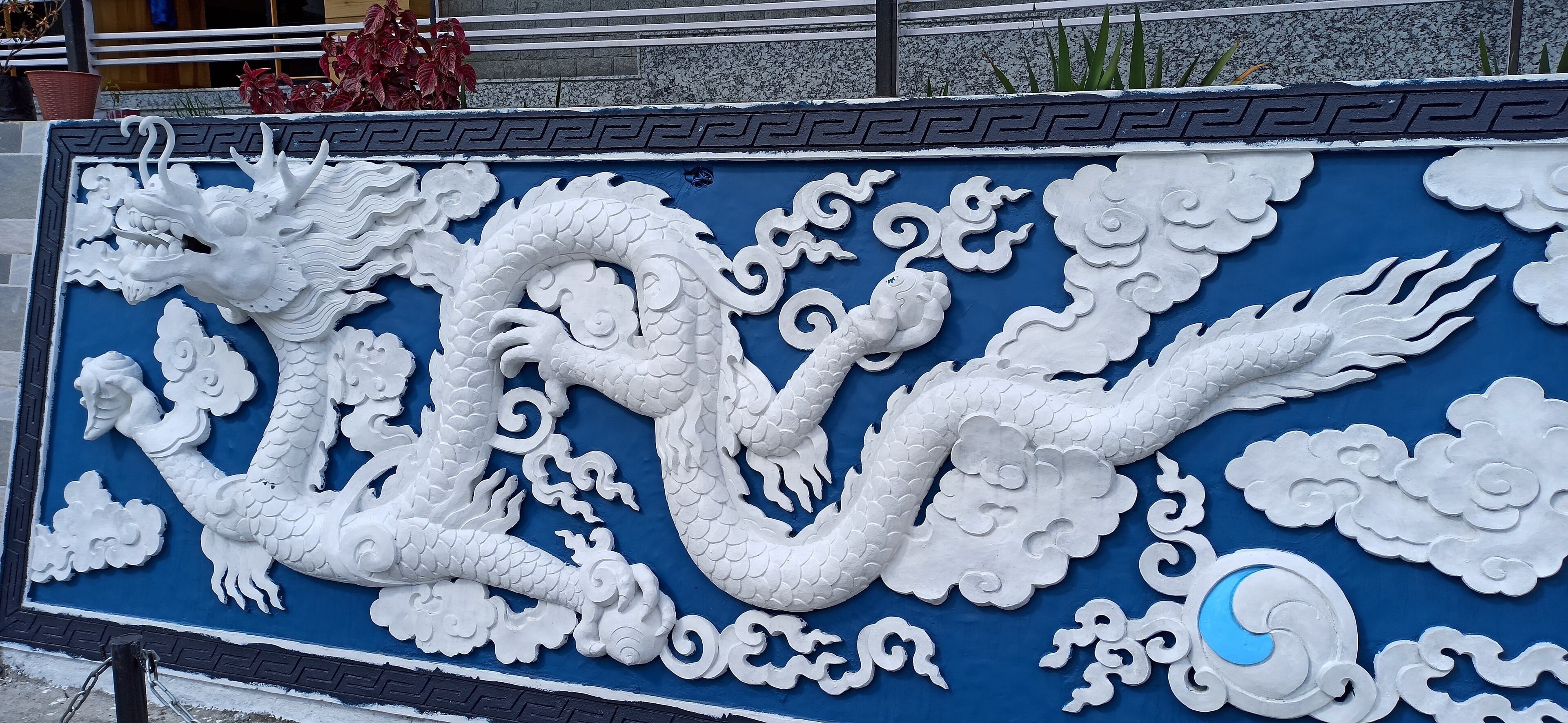 A detailed dragon mural on a blue wall with white clouds and a crescent moon.