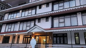 Un edificio de varios pisos con un estilo arquitectónico tradicional, que destaca por su entrada decorativa y una gran escultura ornamentada al frente.