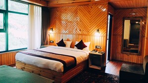 A wooden-paneled bedroom with a large bed, bedside lamps, a mirror, and a view of the outdoors.