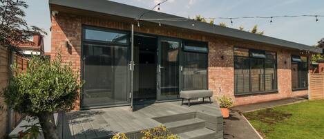 Une maison moderne dotée d’un patio, de plantes en pot et d’un banc.