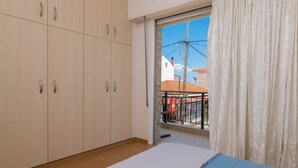 A bedroom with a bed, a sliding glass door to an outdoor area, and a large wardrobe. - Natasas Apartments (Zakynthos)