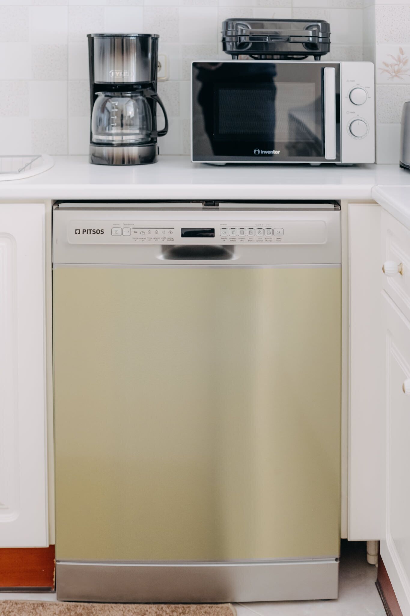 A kitchen with a dishwasher, a coffee maker, and a microwave.