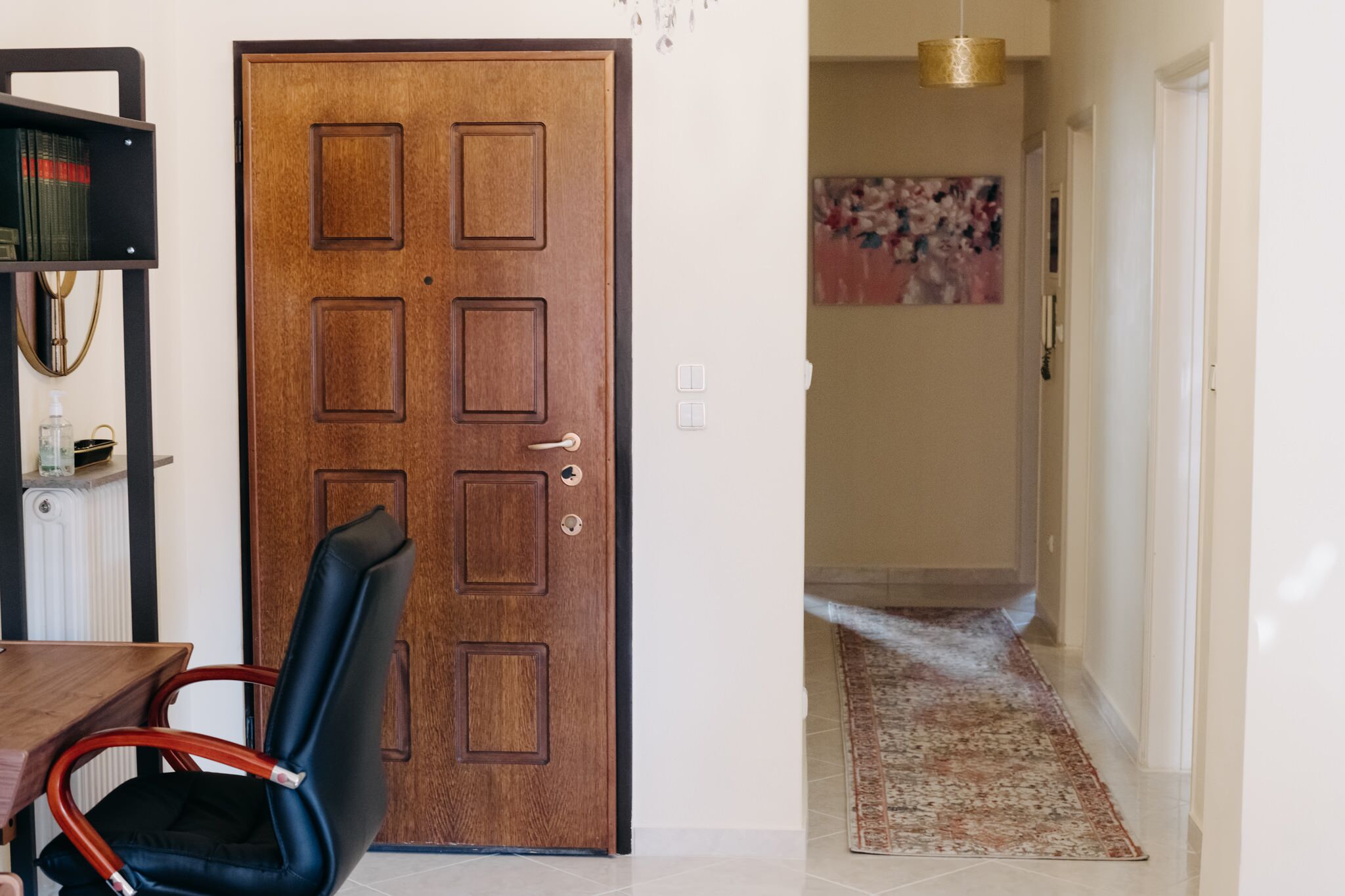 Une porte en bois avec une poignée, une chaise noire, une petite table avec une bouteille et un radiateur.