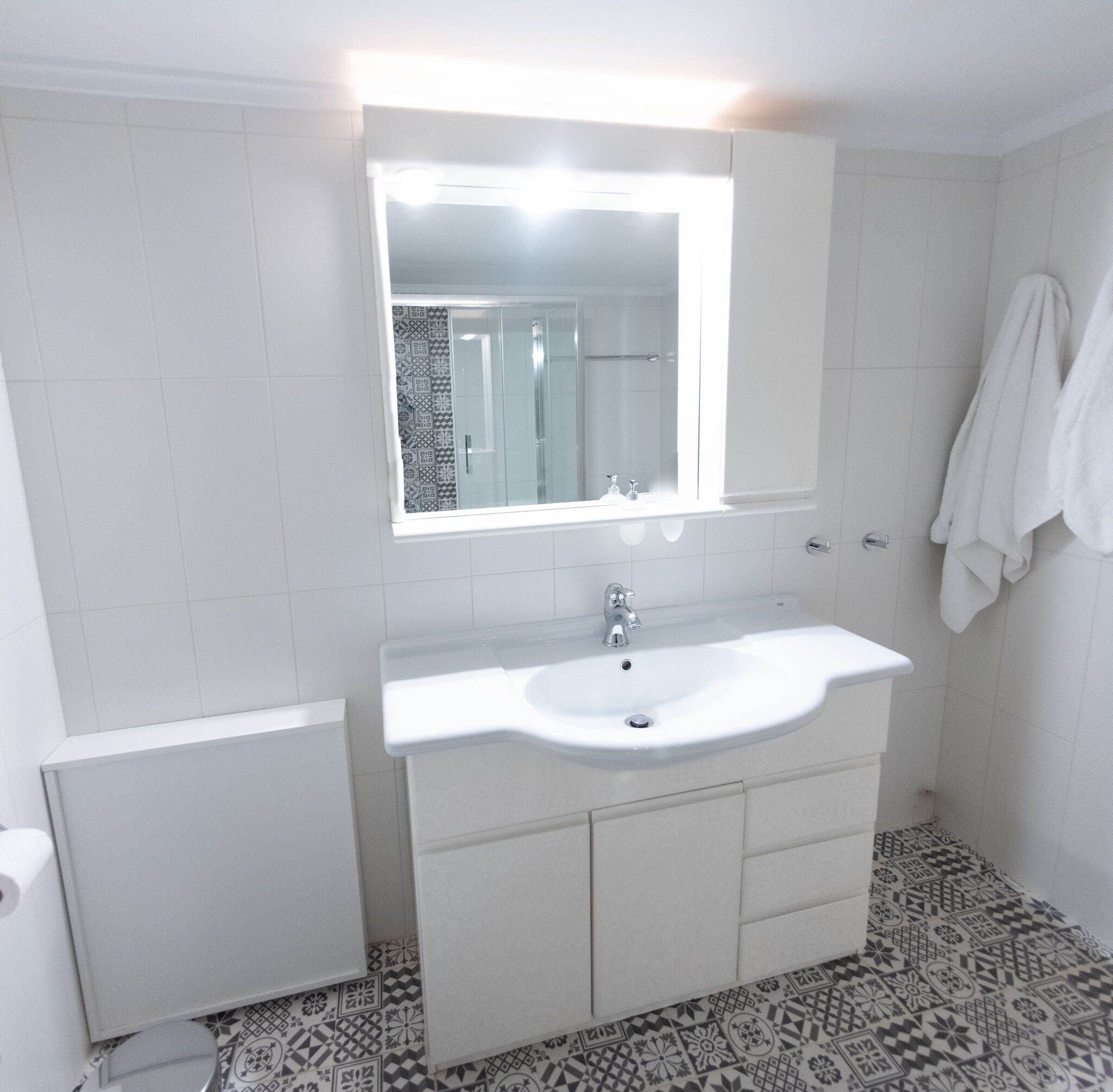 Ein Badezimmer mit einem weißen Waschbecken, einem Spiegel und einem Handtuch an der Wand.