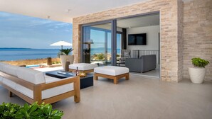 Una sala de estar moderna con un amplio ventanal que da a un balcón con vistas al mar.
