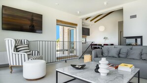 Una sala de estar moderna con un sillón a rayas, un sofá gris, una mesa de centro de mármol y un cuadro grande en la pared.