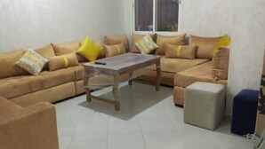 Un soggiorno con un divano beige, un tavolino in legno e un poggiapiedi.