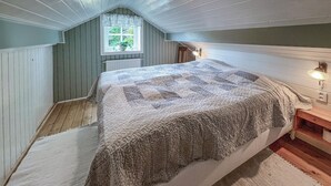 Ein Schlafzimmer mit einem großen Bett, einem Fenster mit Blick auf Grünflächen, einem Heizkörper und einem Nachttisch mit Lampe.