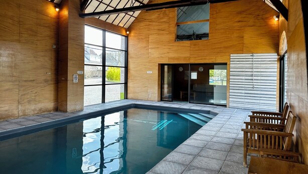 Una piscina interior con paredes de madera y techo inclinado.