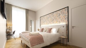 A modern hotel room with a large bed, a desk, and a chair.