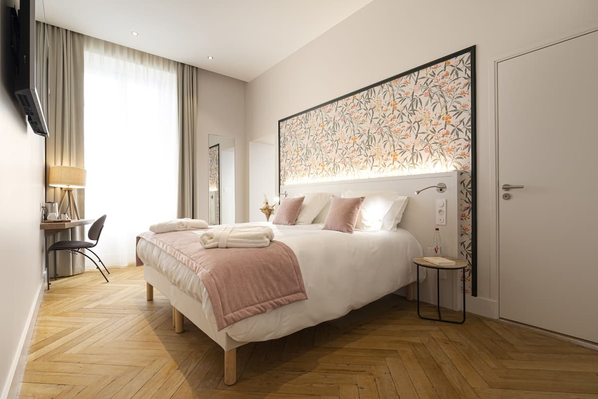 A modern hotel room with a large bed, a desk, and a chair.