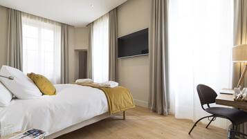 A hotel room with a bed, a desk, a chair, a TV, and curtains.