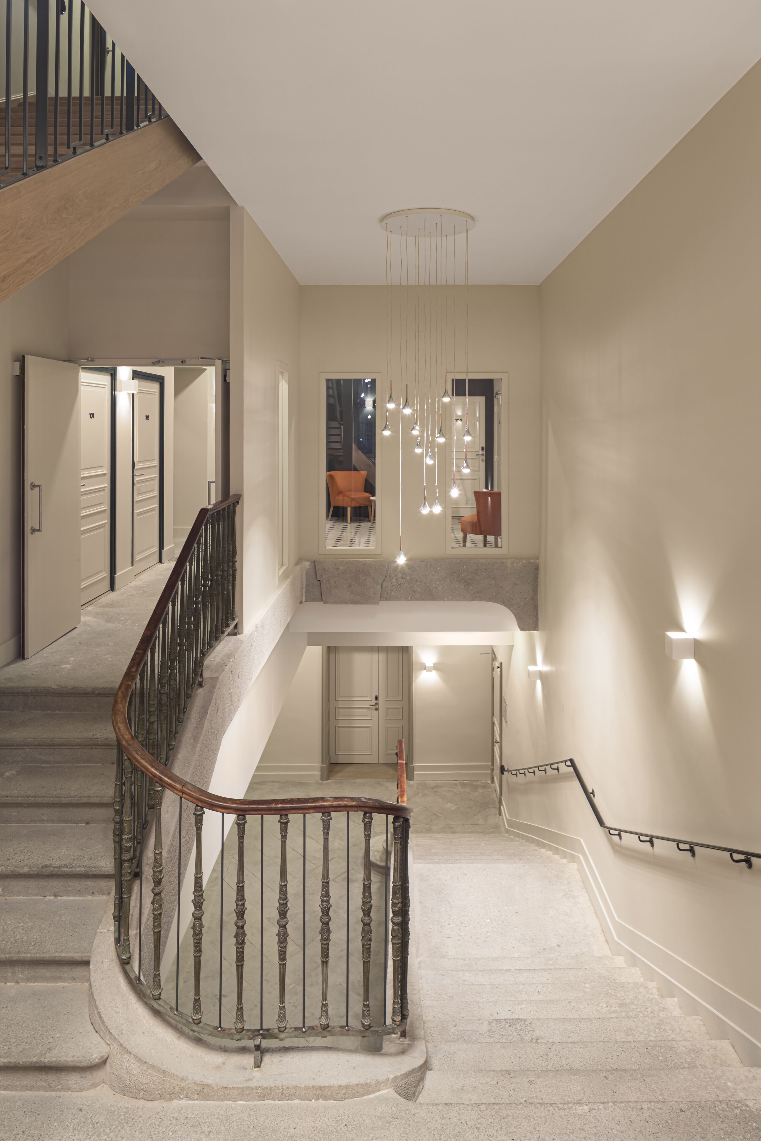 A multi-level interior with a staircase, a seating area, and pendant lighting.