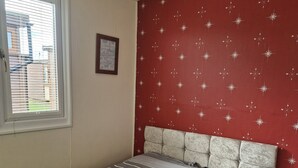 Une chambre à coucher avec un lit, une fenêtre et un mur rouge orné de motifs en forme de boussole.