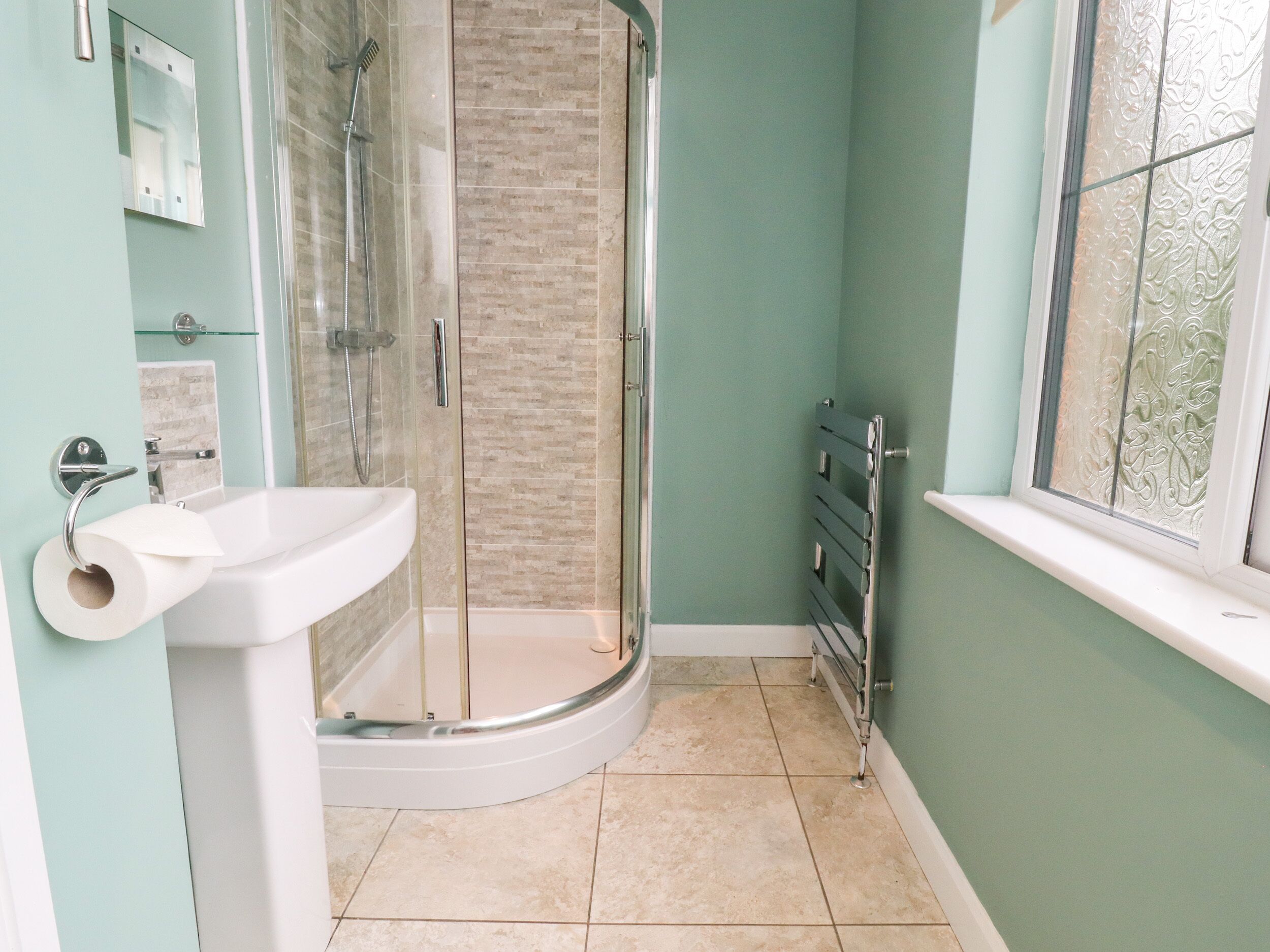 A bathroom with a shower, sink, and window.