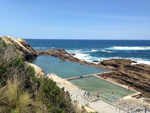 Ein Naturbad, umgeben von Felsen und Wellen des Ozeans.