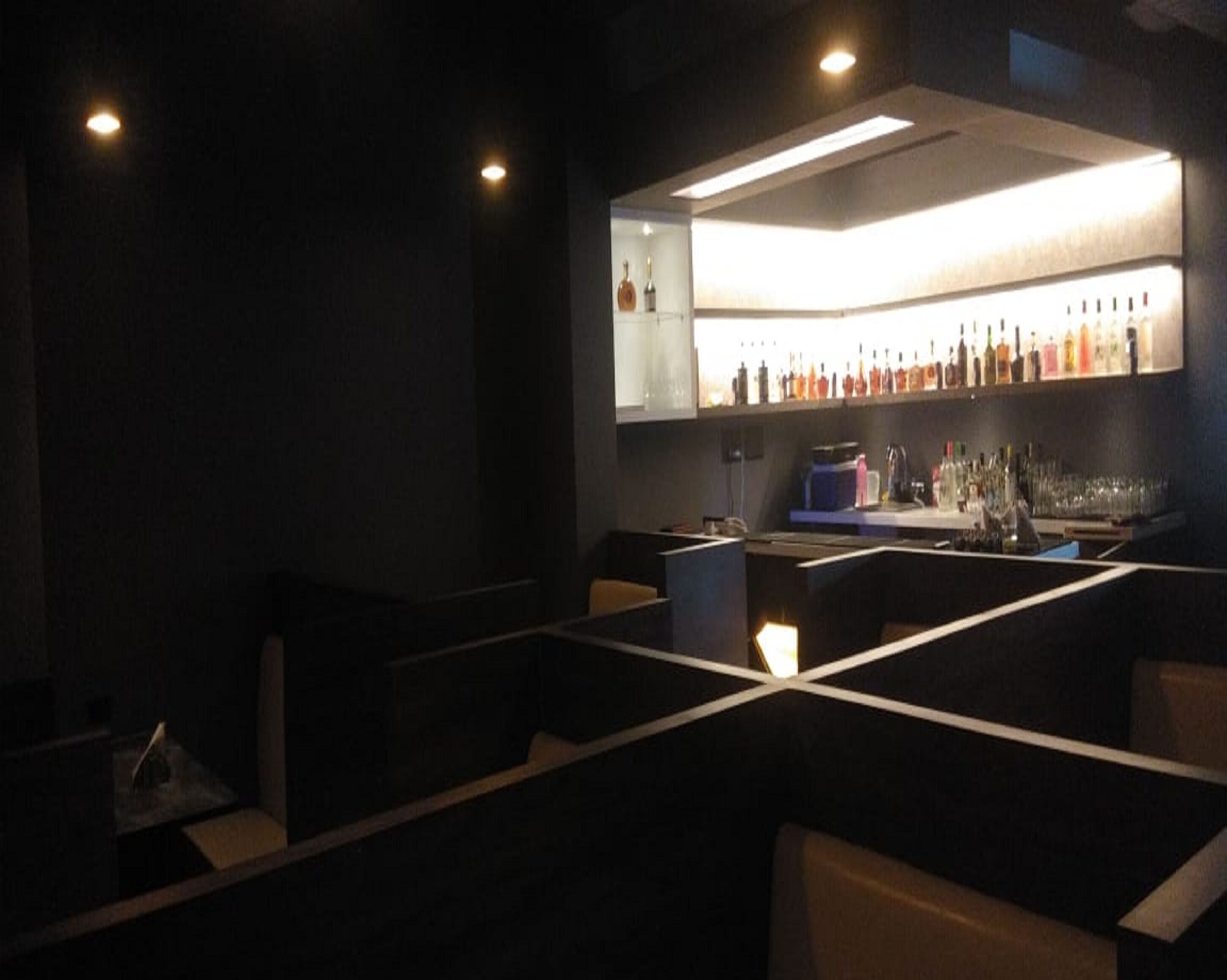 A dimly lit bar area with a counter and seating.