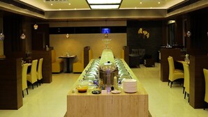 A modern bar area with a long counter, multiple seating options, and a central decorative light fixture. - KRV Meridian (Modakurichi)