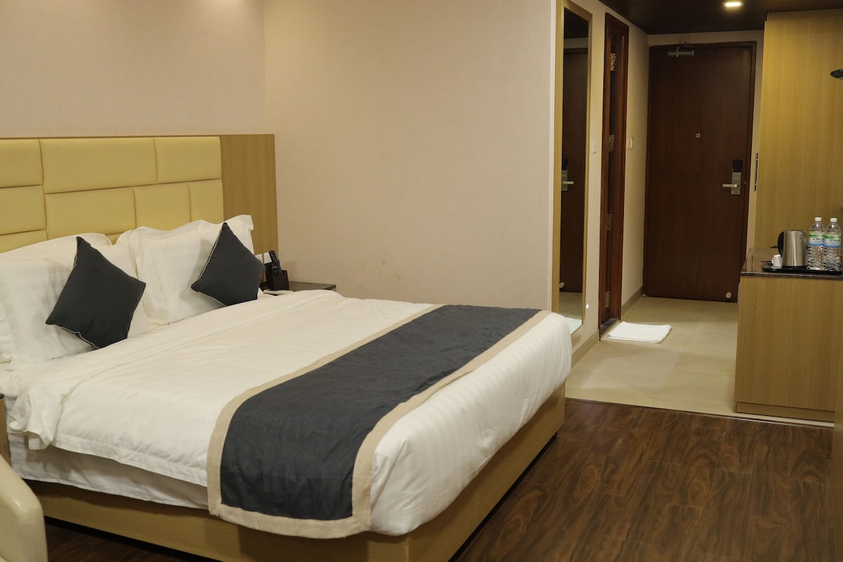 A hotel room with a bed, bedside table, and a wooden wardrobe.