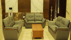 A lobby with three leather sofas and a wooden coffee table. - KRV Meridian (Modakurichi)