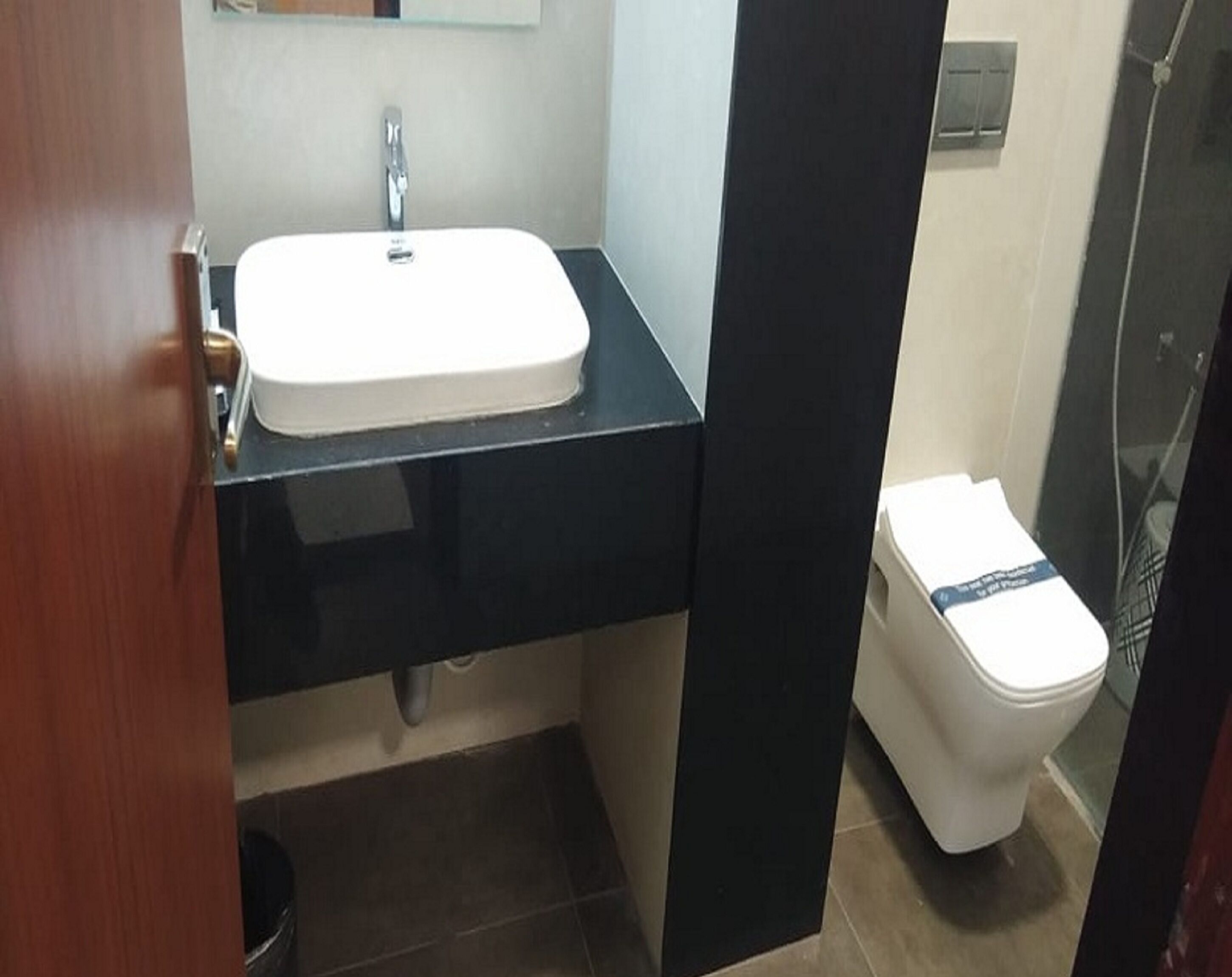 A bathroom with a white sink, black countertop, and a white toilet.